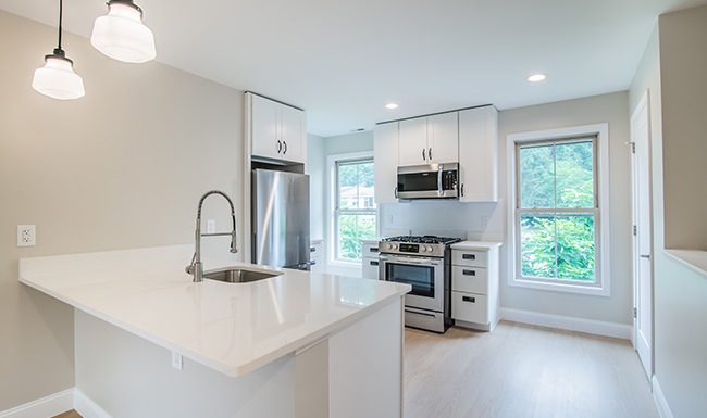 Spacious and well lit kitchen with wood floors and stainless steel appliances